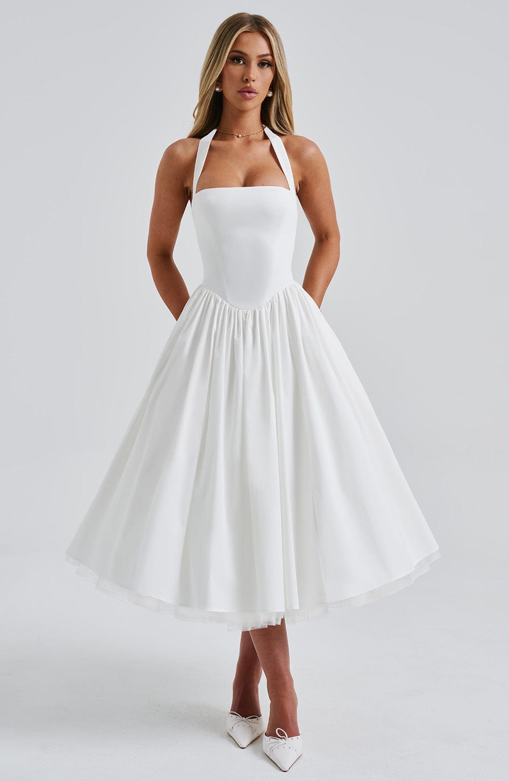 Elegant white halter neck midi dress with a square neckline and full pleated skirt, perfect for wedding guests.