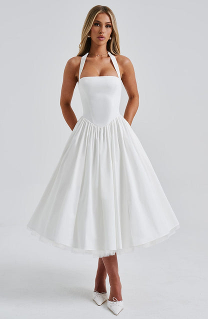 Elegant white halter neck midi dress with a square neckline and full pleated skirt, perfect for wedding guests.
