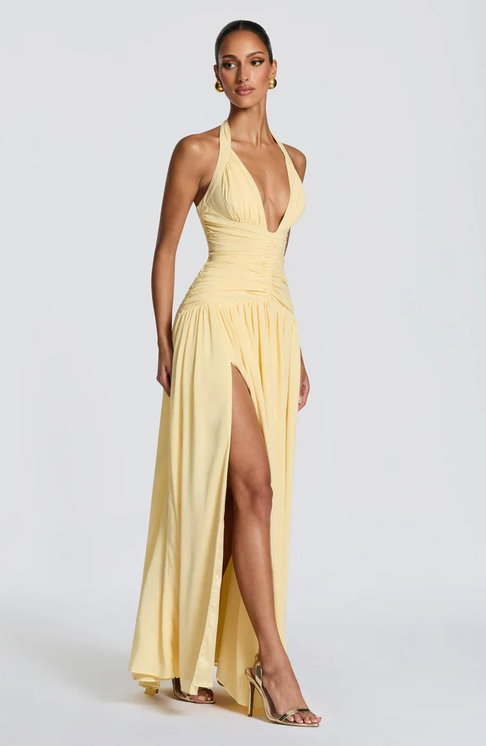 Pale yellow wedding guest halter maxi dress side view with fitted ruched waist and high slit hem