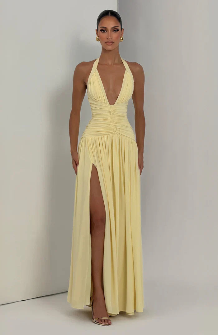 Front view pale yellow wedding guest halter V neck maxi dress with ruched bodice and thigh-high slit