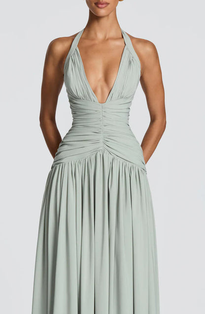 Close-up of sage green halter V neck maxi dress with gathered bust, ruched waist, and draped skirt