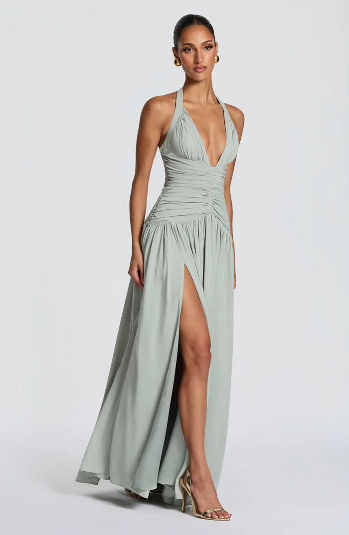 Side pose sage green wedding guest halter maxi dress with flowing skirt and thigh slit detail