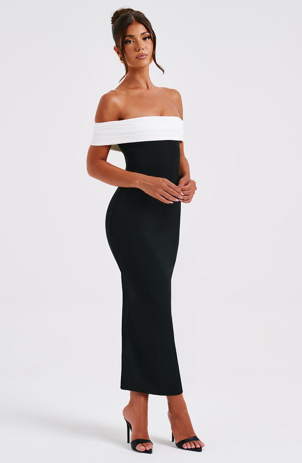 Side profile of a women's black off-shoulder midi dress with a white band, showcasing the bodycon fit.