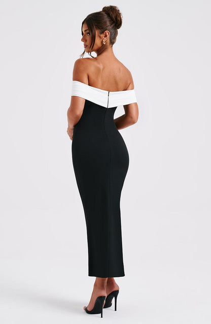 Back 3/4 view of a black off-shoulder midi dress, highlighting the fitted style and subtle back zipper.