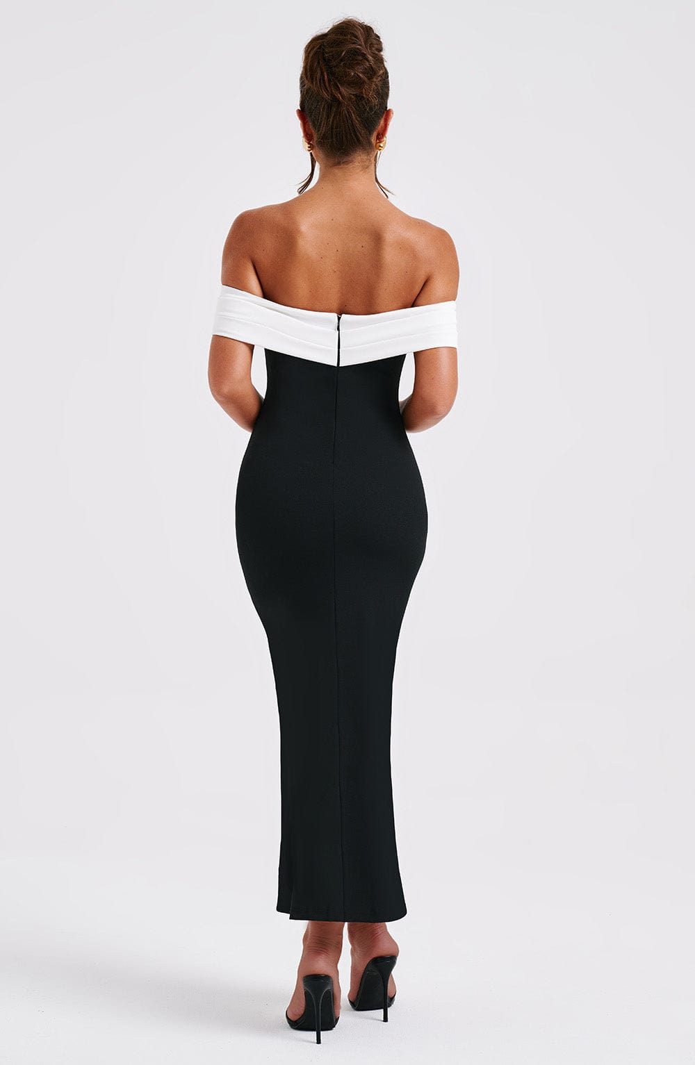 Back view of a black off-shoulder midi dress with a white top band, showing the elegant form-fitting design.