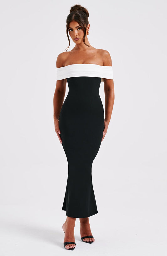 Elegant black and white off-shoulder bodycon midi dress with a sleek silhouette, perfect for wedding guests.