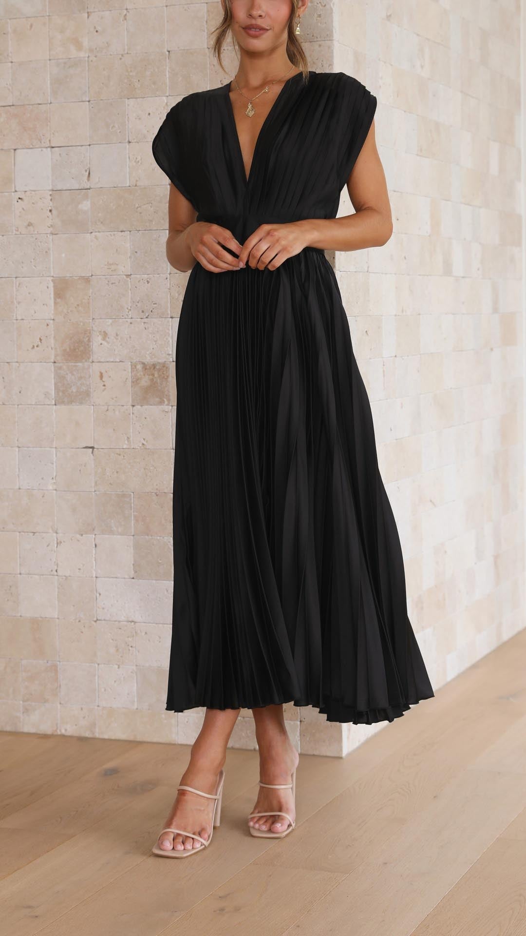 Front view of a black pleated v-neck midi dress, featuring cap sleeves and a flowing skirt, ideal for wedding guests.