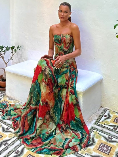 Seated view of strapless printed maxi dress, green red abstract print with long draped hemline