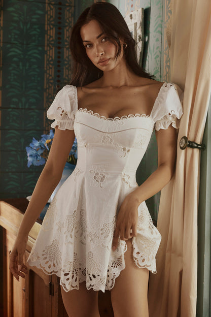Lifestyle shot white broderie anglaise puff sleeve mini dress with fitted bodice and lace cutwork