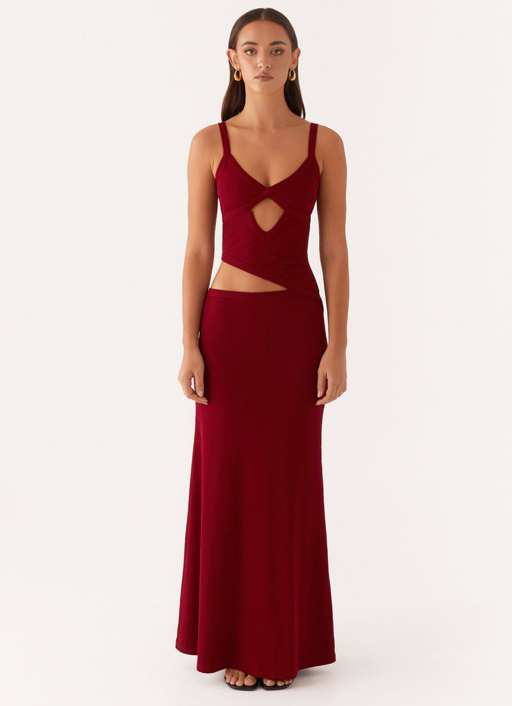 Front view of a women's bodycon maxi dress in deep red with a unique cut-out design at the waist and bust.