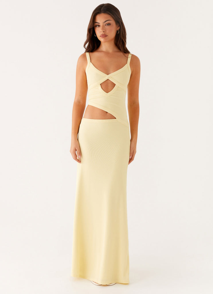 Front view of a women's bodycon maxi dress in light yellow with a unique cut-out design at the waist and bust.