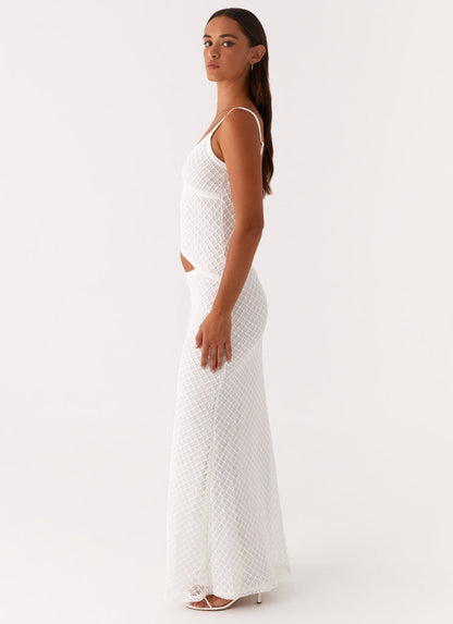 Side profile of a white crochet cut out maxi dress, showing the flowing skirt and strap details.