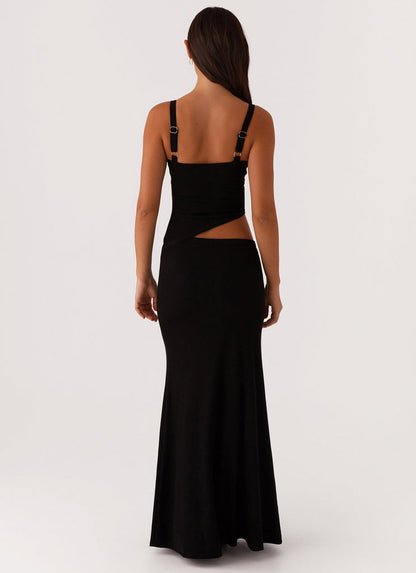 Back view of a black knit maxi dress, highlighting the side cut-out and adjustable strap hardware.