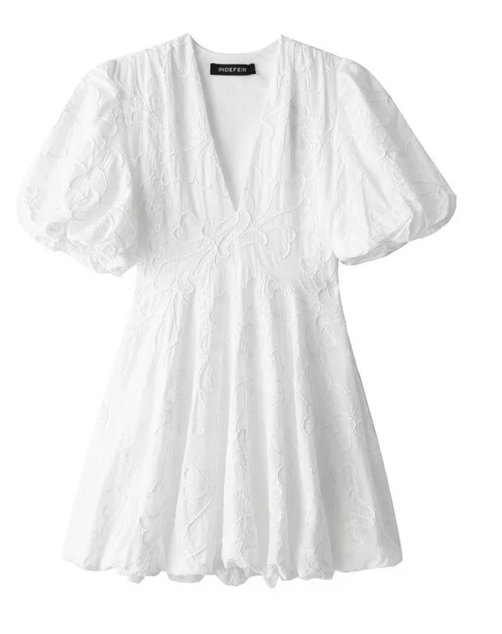 White floral textured v-neck puff sleeve mini dress laid flat showing empire waist seam and A-line skirt