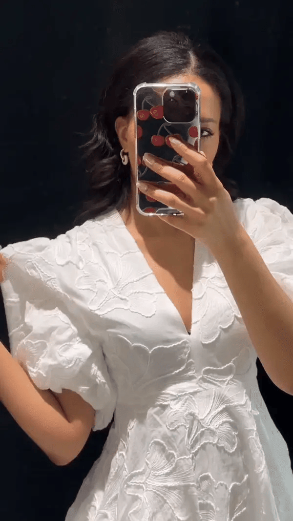 Close-up of white floral jacquard mini dress showing deep v-neckline, puff sleeves, and raised embroidery