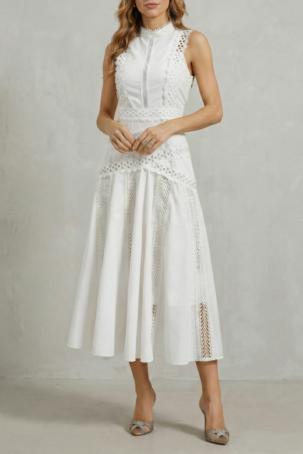 Women's white sleeveless midi dress with high neck, featuring delicate lace paneling and a flowy skirt.