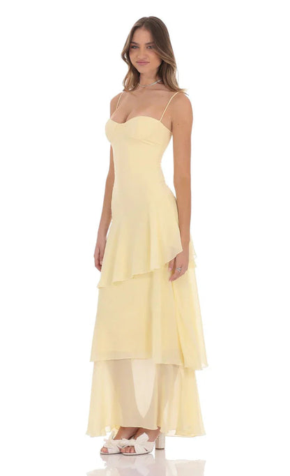 Side view of light yellow tiered ruffle maxi dress, fitted bodice and flowy layered skirt